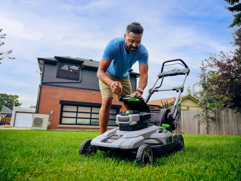 Man with electric lawn mower in yard